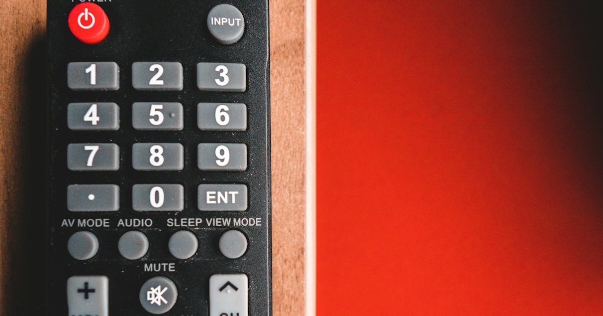 Black TV remote control on red surface